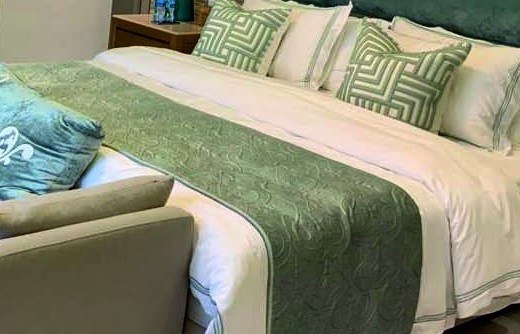 Patterned cushions and a green bed runner